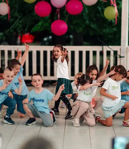 Deca plešu na letnjoj bini, svi sa podignutim prstom u istoj koreografiji