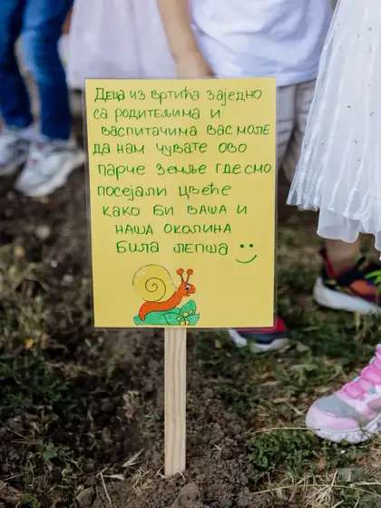 Ručno napisana žuta tablica na drvenom kolcu u sveže prekopanoj leji