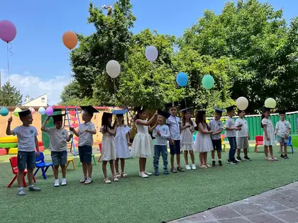 Završna priredba u dvorištu vrtića, deo dece nosi kape za dodelu diploma